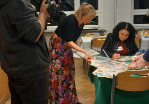 Nauczyciele wypisują dymlomy dla uczestnikówkonkursu w świetle kamery Telewizji Toya